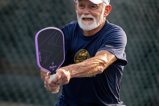 a-old-man-holding-a-purple-pickleball-paddle